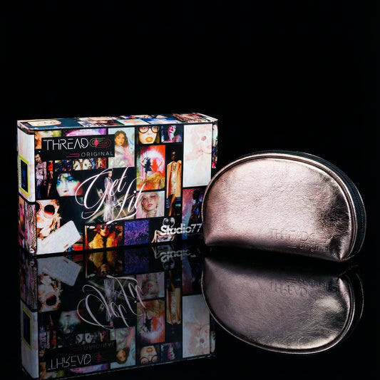 Champagne metallic makeup bag with wipeable insulated lining beside Studio 77 collector gift box. Compact vegan leather cosmetic pouch by Thread Original.